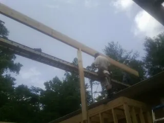 Carpenter setting a ridge beam over a new addition frame — Ice Dam Removal by Roofing Brothers in Whitakers