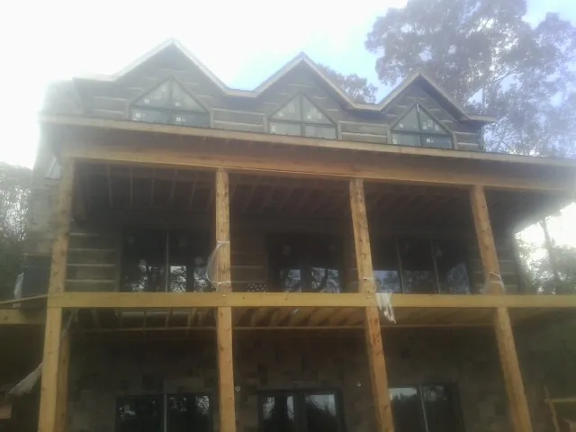 Dormers and porch framing on a large log home under construction — Roof Coating work by our crew in Whitakers