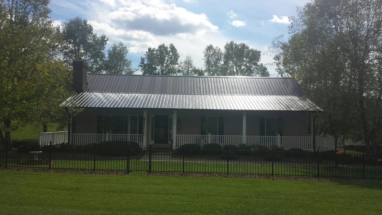 Gray metal roof on a brick ranch with a full width front porch — Gutter Guard Installation work by our crew in Whitakers