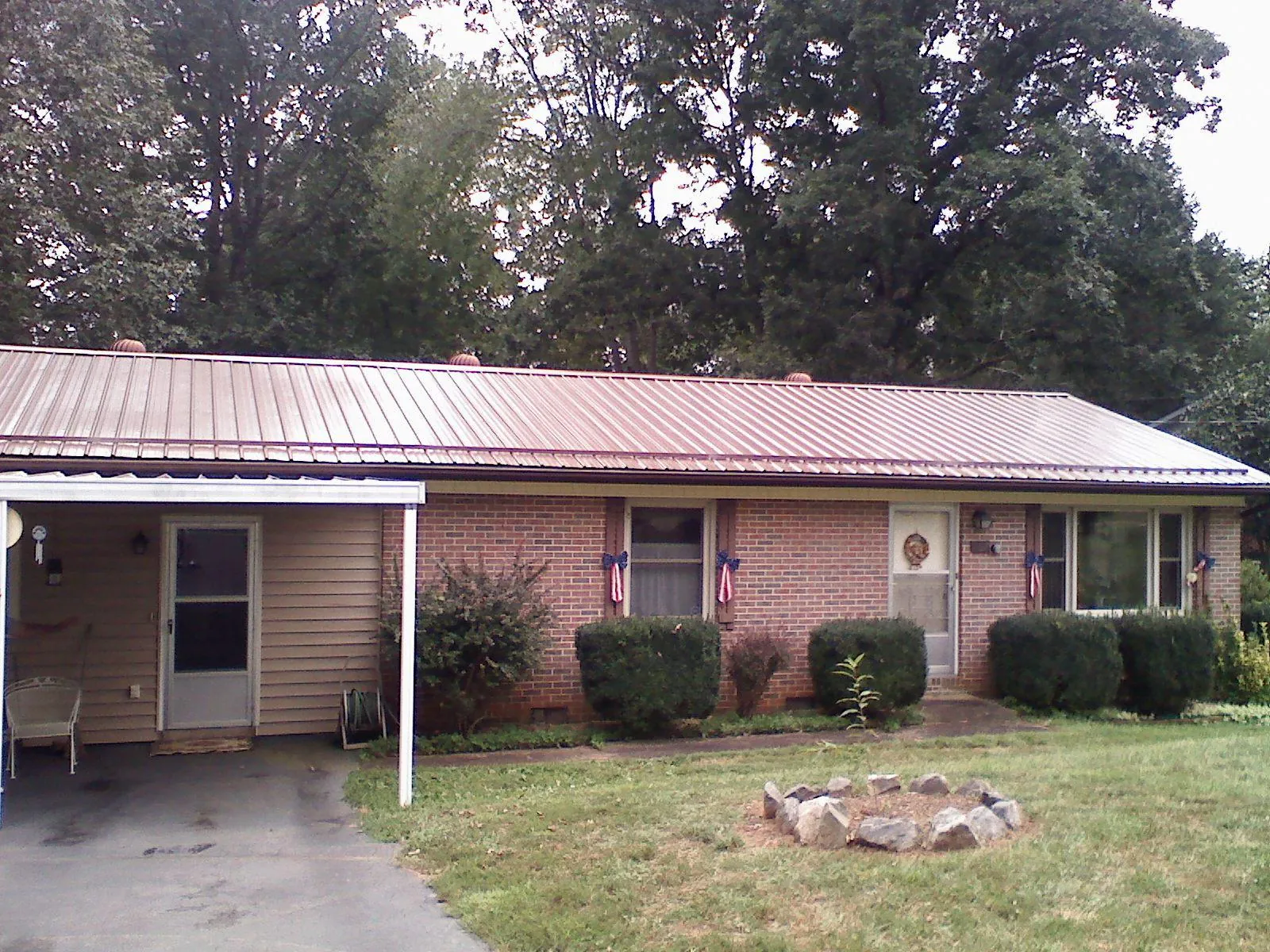 Bronze metal roof and carport on a brick ranch home — Roof Repair work by our crew in Whitakers