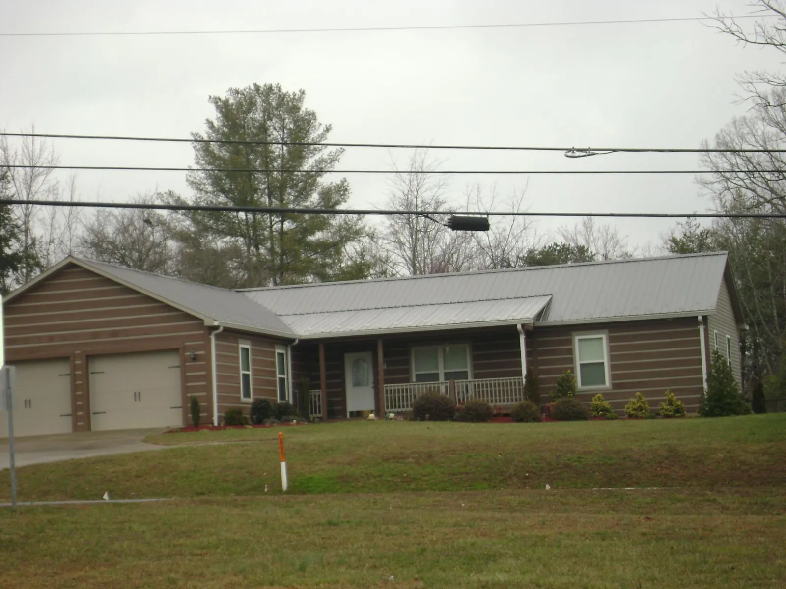 Gray metal roof on a log sided ranch home with a front porch in Whitakers